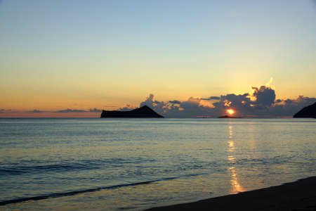 Early Morning Sunrise on Waimanalo Beach on Oahu, Hawaii over Rock Island bursting through the clouds.の写真素材