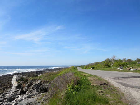 Peaks Island granite rocky Shoreline with road, trees in Maine.の写真素材