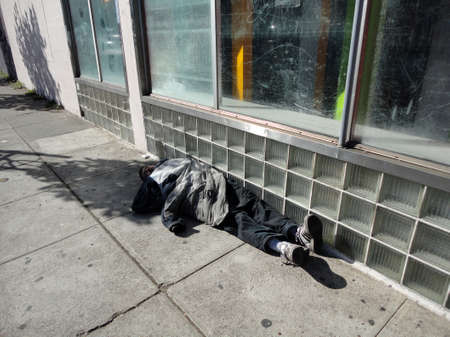 SAN FRANCISCO - NOVEMBER 9: Bundled up homeless person sleep along side of building in the mid-day in San Francisco, homeless population is one of the cities biggest concerns.  November 9, 2010.のeditorial素材