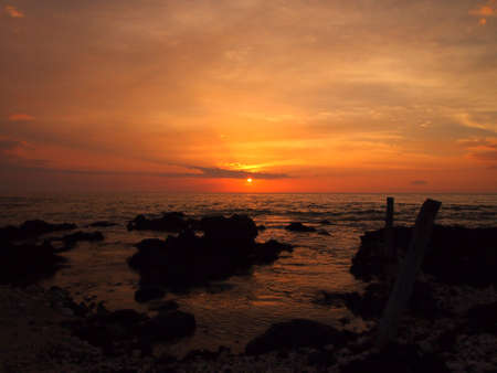Sunset over ocean with lava rocks of Holoholokai Beach in the foreground on the Kohala Coast on the...