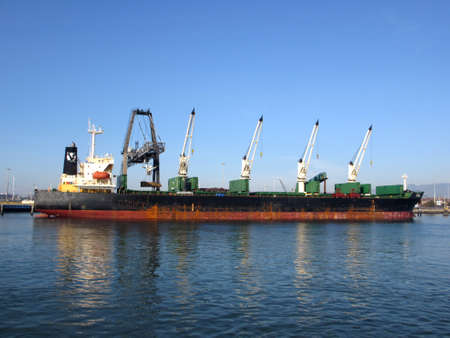OAKLAND - JANUARY 3:  Shipping boat is unloaded by cranes in Oakland Harbor on a clear day. The fourth busiest container port in the country, it's a major economic engine in the San Francisco Bay Area.  January 3, 2012.のeditorial素材
