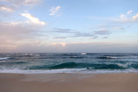 Waves break and crash towards the Hanakailio Beach with dramatic blue cloudy sky on the North Shore of Oahu, Hawaii.の写真素材
