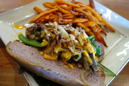 Pipikaula Cheese Steak with Sweet Potato fries - Classic dried beef seared with green peppers and onions topped with our house-made nacho cheese and crispy onion garnish and Sweet Potato fries on the side.の写真素材