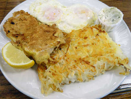 Breaded and fried BREAKFAST Mahi Mahi AND With two eggs served with hash brown potatoes, tartar sauce, and lemon slice.の写真素材
