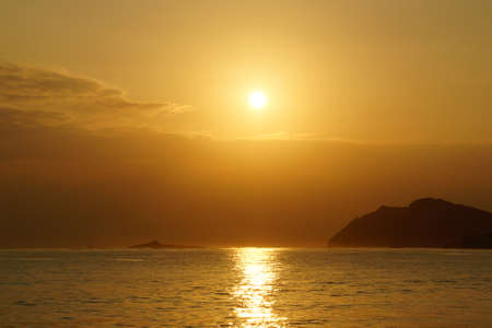 Sunrises in between Kaohikaipu (Black/Turtle) Island and Makapuu with sunlight reflecting on the ocean water of Waimanalo bay on Oahu, Hawaii.の写真素材