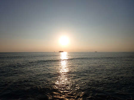 Sunset over the Pacific Ocean with light reflecting on water and boats moving on the horizon off the coast of Oahu, Hawaii.の写真素材