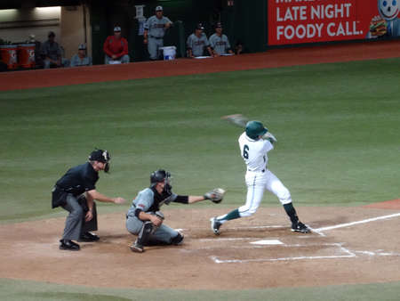 HONOLULU, HI - APRIL 17: UH Batter swings at incoming pitch with catcher and umpire behind him during a night game at UH Baseball Les Murakami Stadium in Manoa, Honolulu, Hawaii April 17, 2015.のeditorial素材