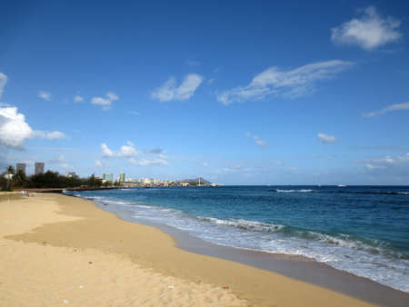 Sand Island Beach with Downtown Honolulu, Diamond head Crater in the distance on Oahu, Hawaii and waves lapping in the ocean.の写真素材