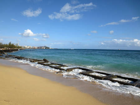 Old military water break on Sand Island Beach with tugboat on horizon and downtown Honolulu in the distance on Oahu, Hawaiiの写真素材