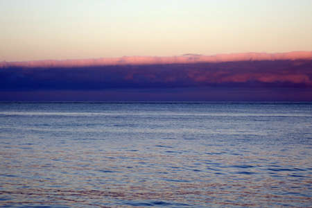 Calm ocean waters of Waimanalo Bay at dusk with clouds hanging overhead on Oahu, Hawaii.の写真素材