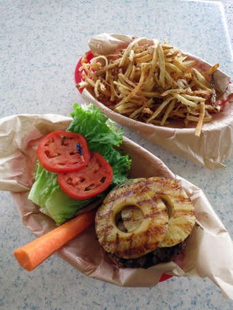 Open Face Hawaiian style burger with pineaple topping, lettuce, tomatoes, carrot with side of French fries.の写真素材