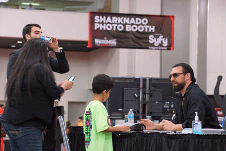SAN JOSE - MARCH 28: Damien Sandow talks to kid fan as mom takes photo on cellphone and he signs magazine at WWE Axxess event at the McEnery Convention Center in San Jose, California on March 28, 2015.のeditorial素材