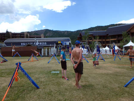 SNOWMASS, CO - JULY 4:  Yogaslacker People balance on slacklines during Wanderlust festival at Snowmass Village area with mountains, building, ski lift, and trees in Colorado on July 4, 2015.のeditorial素材