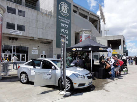 OAKLAND, CA - OCTOBER 15: Chevy Cruze on display at ballpark with door open as people sign-up for t-shirts before Oakland A's baseball Game May 15, 2011 Oakland Coliseum, CA.のeditorial素材