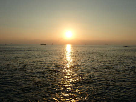 Sunset over the Pacific Ocean with light reflecting on water and boats moving on the horizon off the coast of Oahu, Hawaii.の写真素材