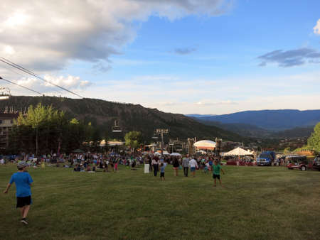 SNOWMASS, CO - JULY 2:  People and kids watch concert on field with ski lift during Wanderlust festival at Snowmass Village area mountains, with condos, road, and trees in Colorado on July 2, 2015.のeditorial素材