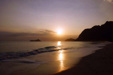 Early Morning Sunrise on Waimanalo Beach on Oahu, Hawaii over Rock Island bursting over the clouds.の写真素材
