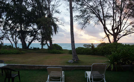 Lawn chairs in beach yard looking towrds Early Morning Sunrise on Waimanalo Bay bursting through the clouds on Oahu, Hawaii.の写真素材