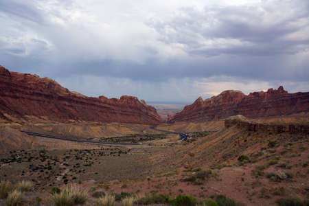 Road winds through Spotted Wolf Canyon with dramatic clouds in sky in Utah, USA.の写真素材