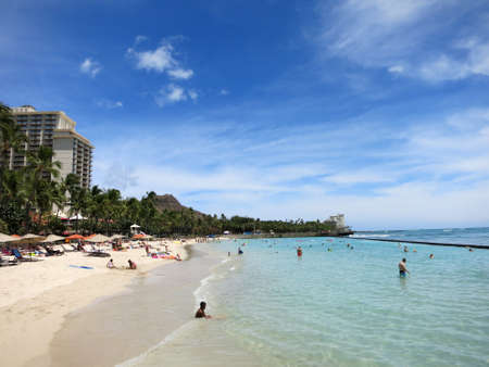 WAIKIKI - JUNE 16: People play in the water and hang out on the beach in world famous tourist area Waikiki on a beautiful day with Diamond head and hotels in the distance.  June 16 2015 in Waikiki, Hawaii.のeditorial素材