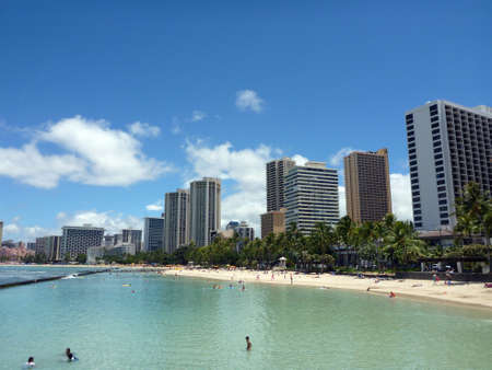 WAIKIKI - JUNE 17: People play in the protected water and hang out on the beach in world famous tourist area Waikiki on a beautiful day with hotels in the distance.  June 17 2014 in Waikiki, Hawaii.のeditorial素材