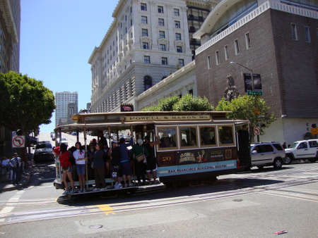 SAN FRANCISCO - JULY 2: Antique Cable Car rides down  Powell Street with people hanging on side on July 2, 2010 in San Francisco, California, USA.のeditorial素材