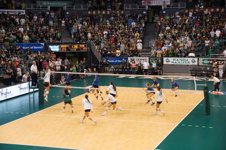 HONOLULU, HI -  SEPTEMBER 25: UH player jumps to hit volleyball as UCSB Women's players jump to block Volleyball during game. September 25, 2015 Honolulu, Hawaii.のeditorial素材