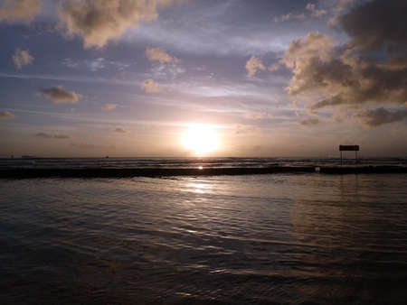 Dramatic Sunset on waters of Waikiki with boats on Horizon and silhouette of sign on Oahu, Hawaii.の写真素材