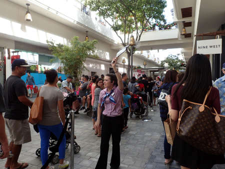 HONOLULU, HI - NOVEMBER 26:  Woman holds up Doland Duck paddle to Crowd of People in linr at mall on Black Friday at the Ala Moana shopping center. taken on November 26, 2015 at Ala Moana Shopping center in Honolulu, Hawaii.のeditorial素材