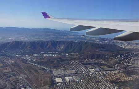 SAN FRANCISCO - OCTOBER 13: Wing of Hawaiian Airlines plane flying in the air above city of San...
