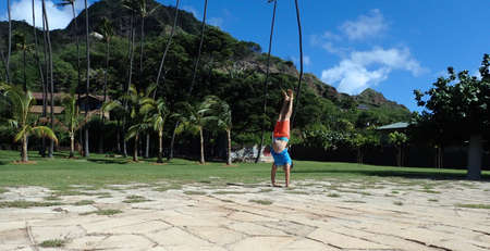 Man Handstanding stone foundation in Leahi Beach Parki with Coconut trees and Diamondhead in the background on Oahu, Hawaii on a beautiful day.の写真素材