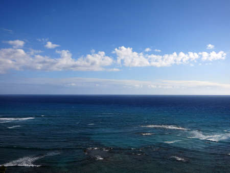 Shallow wavy ocean waters of Waikiki looking into the pacific ocean with blue sky and clouds on Oahu.の写真素材