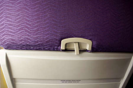 Close-up of Back of Airplane Seat with Purple Clothe and tray table.の写真素材