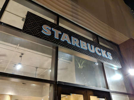 Waikiki - June 8, 2018:  Starbucks White lettering Sign above store at night.  Starbucks Corporation is an American coffee company and coffeehouse chain. Starbucks was founded in Seattle, Washington in 1971. As of 2017, the company operates 27,339 locatioのeditorial素材