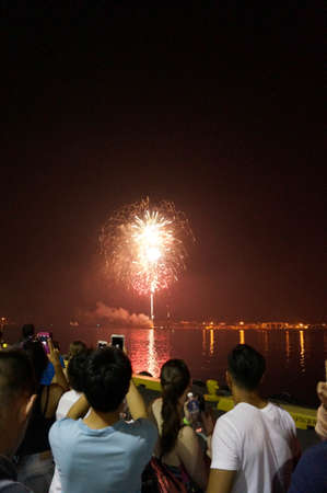 Honolulu - January 1, 2016: New Years Fireworks burst in the air as people watch and record display...