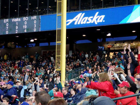 SEATTLE - JUNE 24: Fans in bleachers do the wave with scoreboard above featuring Alaska Airlines ad at Safeco Field during baseball game, Seattle in June 24, 2016.のeditorial素材