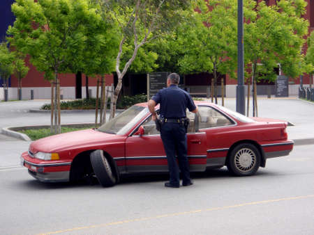 San Francisco - April 28, 2009: Police officer looks at Red Car with front broken wheel at UCSF...