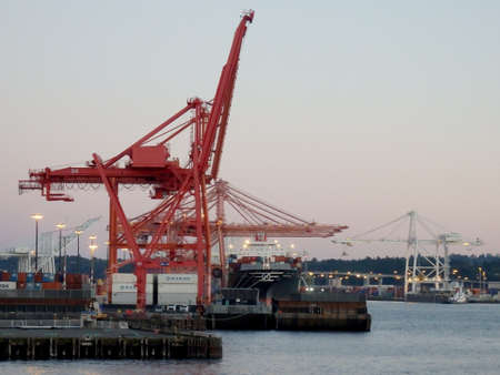 Seattle - June 25, 2016: Red and White Cranes unloaded cargo at dusk in Seattle harbor.のeditorial素材