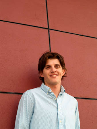 Portrait head shot of a handsome twentysome man with blue eyes against a red wall with black linesの写真素材