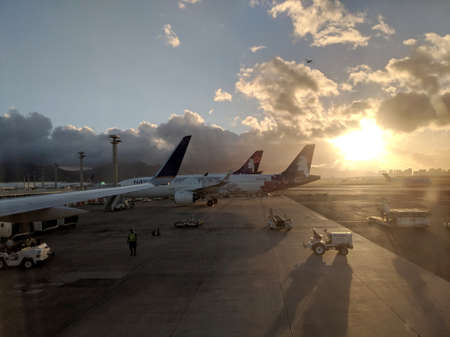 Honolulu - October 25, 2018: Hawaiian Airlines Planes parked at Honolulu International airport waiting to load up into plane for their next flight in the morning during sunrise.のeditorial素材