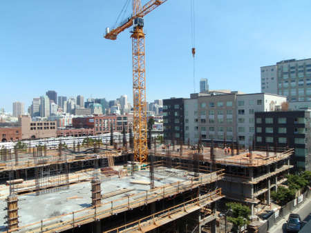 San Francisco - June 13, 2008: People and Crane works at High-rise Construction site high up in San Francisco with Caltrain and great skyline in the distance.のeditorial素材