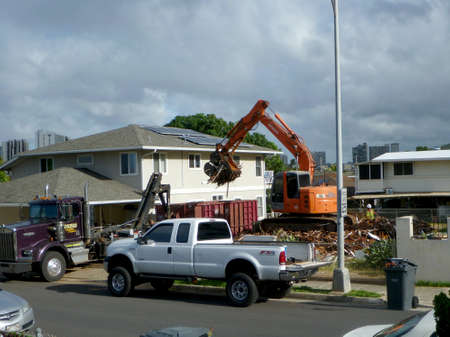 Honolulu - June 24, 2013: Construction Hitachi Bulldozer tears down home and lots material into...