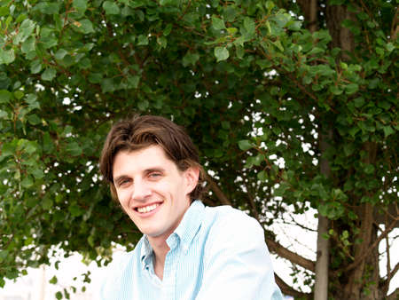 Portrait head shot of a handsome man twenty some, Actor Tony Wyban, with blue eyes and tree background.の写真素材