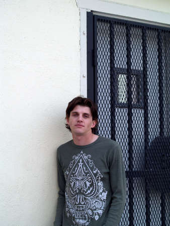 Portrait head shot of a handsome twentysome man with blue eyes against a white wall with door.の写真素材
