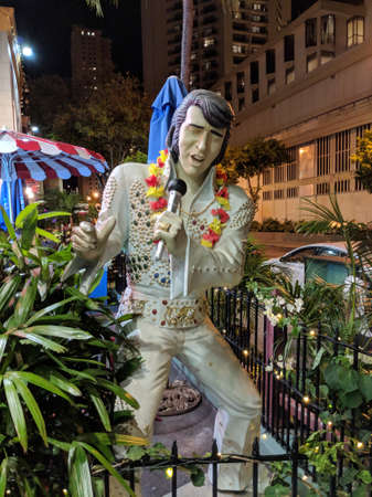 Waikiki - June 28, 2018: Elvis Presley, the king of rock-n-roll, statue singing while wearing a lei outside a restaurant at night.のeditorial素材