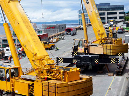 Seattle - May 18, 2019: Two Over Size Load portable Barnhart Cranes works on the tear down of State Route 99 along Seattle seaboard with Marriot in distance.  It was a double-decked highway system known as the Alaskan Way Viaduct which was replaced with aのeditorial素材
