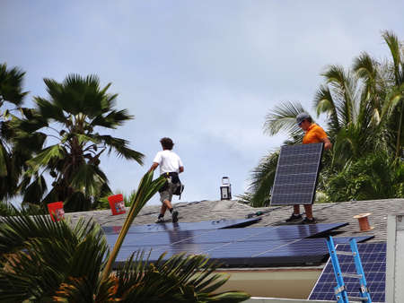 Honolulu - August 29, 2012: Workers install Solar panels array on roof of house in Honolulu, Hawaii.のeditorial素材