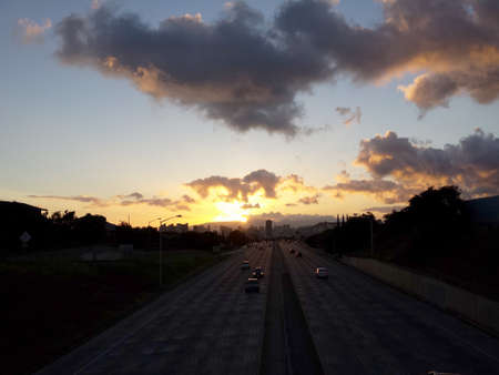 Sunset over Waianae Mountains with Car racing along H-1 Highway in Honolulu, Hawaii.の写真素材
