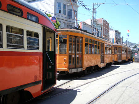 San Francisco - June 28, 2009: Two Orange historic streetcar of the F-Line MUNI Train, original from Milan, Italy, and two other trains parked on street in the Castro district.のeditorial素材
