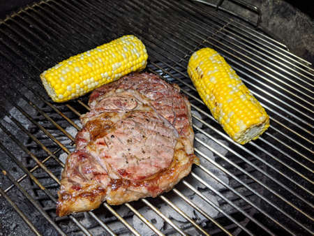 Steak and Two pieces of Corn cooking on a grill.の写真素材